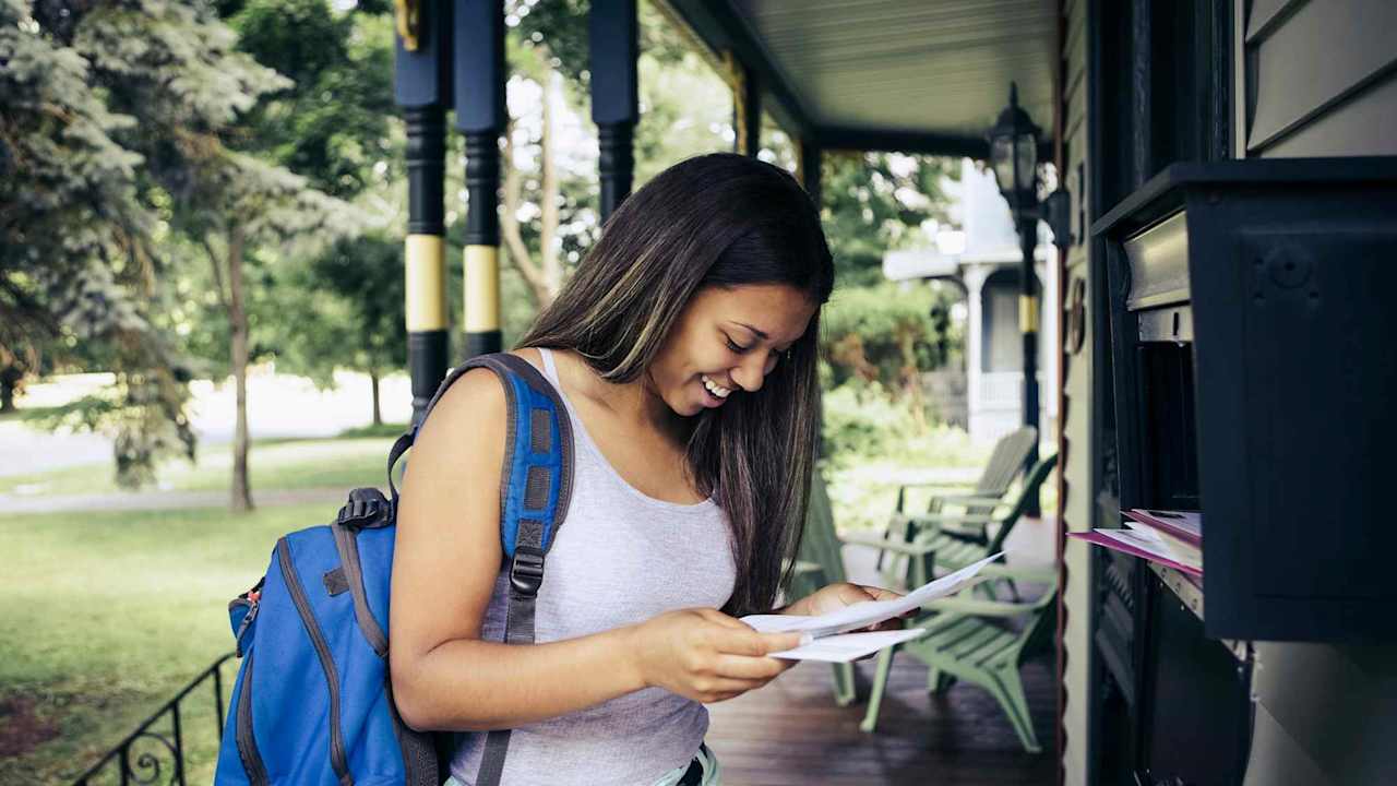 Teenage girl receiving letter of acceptance for college in mail
