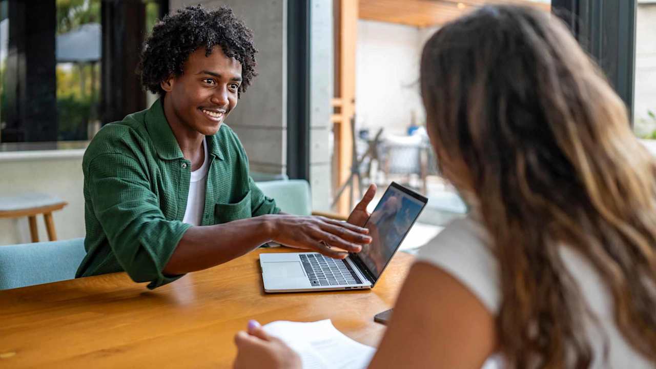Two People Collaborating On Laptop