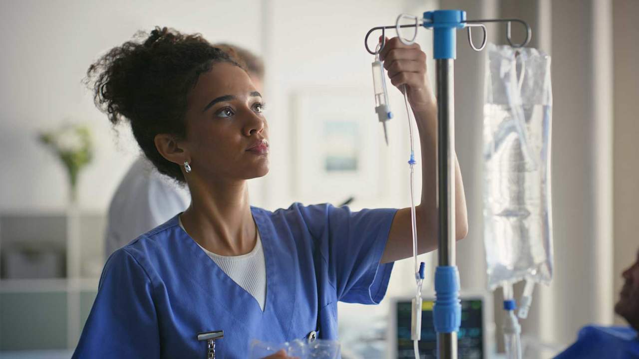 Healthcare, nutrition and nurse with drip, woman and infusion of IV medication and medical professional.