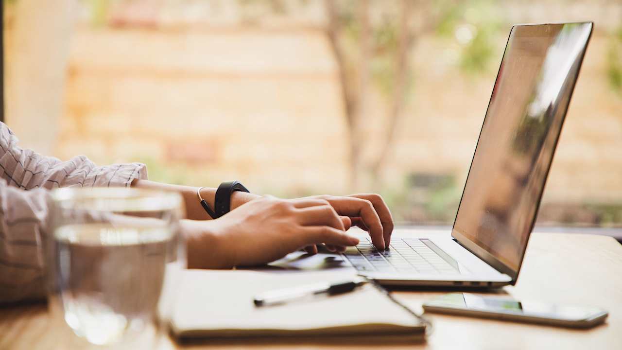 Woman using a laptop at home to update her resume.