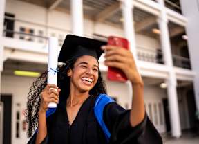 Young woman taking a selfie with her diploma on the graduation