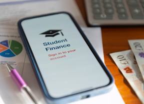 Smart phone screen that reads "Student Finance - Sign in to your account" on a desk with financial documents