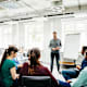 An engineering tutor speaking to his students during a seminar in a bright, modern lab at a university.