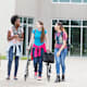 Disabled student using a walker chats with her friends while walking to class on a college campus.