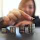 Businesswoman holding and stacking coins on the table