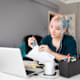 College student sitting at her desk at home stapling pages for a class report..