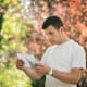 A young man looks surprised as he reads a letter outside.