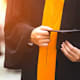 Close up of a graduate holding a graduation cap.