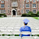 College student sitting in an empty open-air auditorium on campus, after the graduation ceremony.