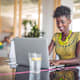 Portrait of a confident businesswoman typing on a laptop while sitting at a table