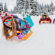 A group of college-aged friends have fun sledding outdoors on a snowy day.