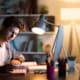 A student is working in a dimly lit space with a computer and a notebook.