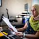 Muslim woman sitting at a desk looking over some documents