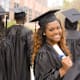 Excited Black female college graduate holding her diploma walks with classmates after the graduation ceremony.