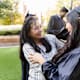 The mature adult mother and the mid adult daughter embrace joyfully after the graduation ceremony.