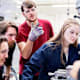 Group of students surrounding a milling machine to work out how they can finish their task together.