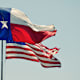 The Texas state flag in the wind next to the United States flag.