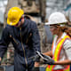 Female Machinery Engineer and male technical in safety protective wear while discuss with using tablet computer. They standing near CNC milling machine.