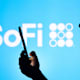BRAZIL - 2022/04/12: In this photo illustration, a woman's silhouette holds a smartphone with the SoFi Technologies logo in the background. (Photo Illustration by Rafael Henrique/SOPA Images/LightRocket via Getty Images)