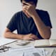 Man With Head In Hands Calculating Bills