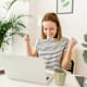 Cheerful young woman celebrating her achievement while reading good news on laptop from home office - Smiling female expressing excitement working at home