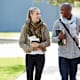 A Black male and white female college student hang out and chat while walking to class on campus.