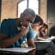 Black male student taking a standardized test in a university classroom.