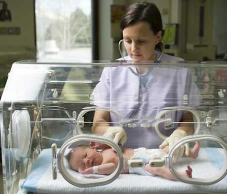 Neonatal nurse checking baby's heartbeat in NICU