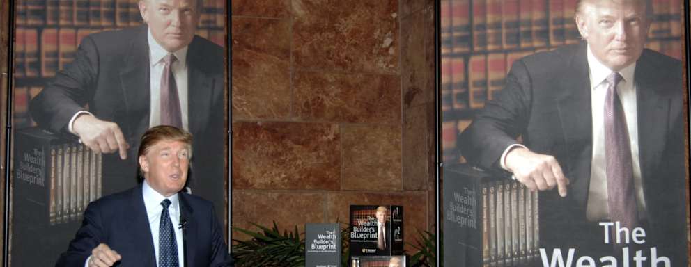 Donald Trump speaks at a podium on his book, The Wealth Builders Blue Print