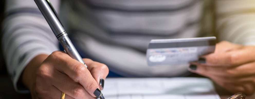 Young woman in her 20s paying uses her credit card to pay her monthly student loan bill.