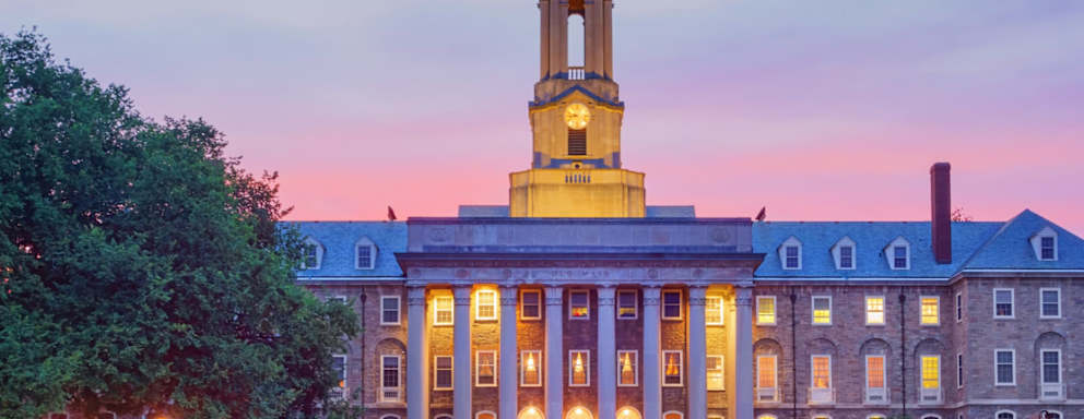 Students chat in front of Old Main, the main administrative building of Penn State after sunset. It is located at University Park in State College, Pennsylvania, USA. Pennsylvania State University (commonly referred to as Penn State or PSU) is a public university with campuses and facilities throughout Pennsylvania.