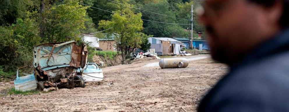 Damaged homes, vehicles, and land where homes used to stand are seen past Chase Hays as he stands near his house in Lost Creek, Kentucky, on September 29, 2022. - Chase Hays is "torn": after seeing floods ravage his hamlet in the Appalachian mountains, he filed a complaint against the mine that overlooks it, but this 34-year-old American does not want to be perceived as an "enemy" of coal. Like him, people in eastern Kentucky are struggling to challenge an industry that has long offered the only well-paying jobs in the region. And in the run-up to the midterm elections, few candidates dare to talk to them about climate change. (Photo by Stefani Reynolds / AFP) (Photo by STEFANI REYNOLDS/AFP via Getty Images)