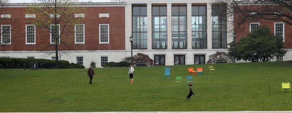 BALTIMORE, MARYLAND - MARCH 28: A couple throw a frisbee for a dog on the campus of The Johns Hopkins University on March 28, 2020 in Baltimore, Maryland. The school is shut down due to the coronavirus (COVID-19) outbreak. (Photo by Rob Carr/Getty Images)