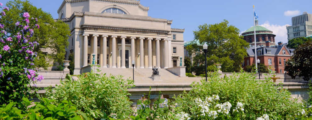 Low Memorial Library at Columbia University in New York City on a sunny spring day. The statue "Alma Mater," installed in 1904 and sculpted by Daniel Chester French, is located midway up the library steps.