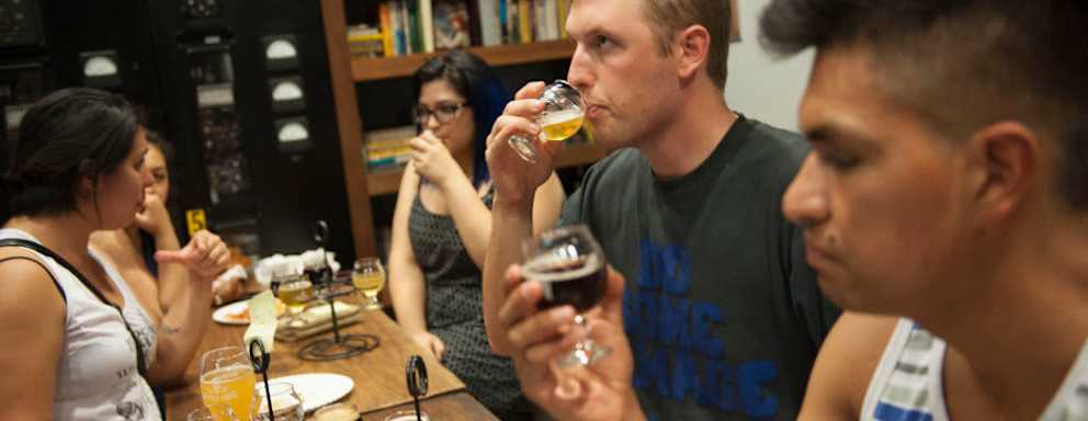 Geography major Cameron Isaac, 23, center, tastes a craft beer sample as Pedro Chacon, at right, examines a beer during a recent meeting of the Cal State Fullerton Craft Beer Advocacy and Home Brew Club at Bottle Logic Brewing in Anaheim.