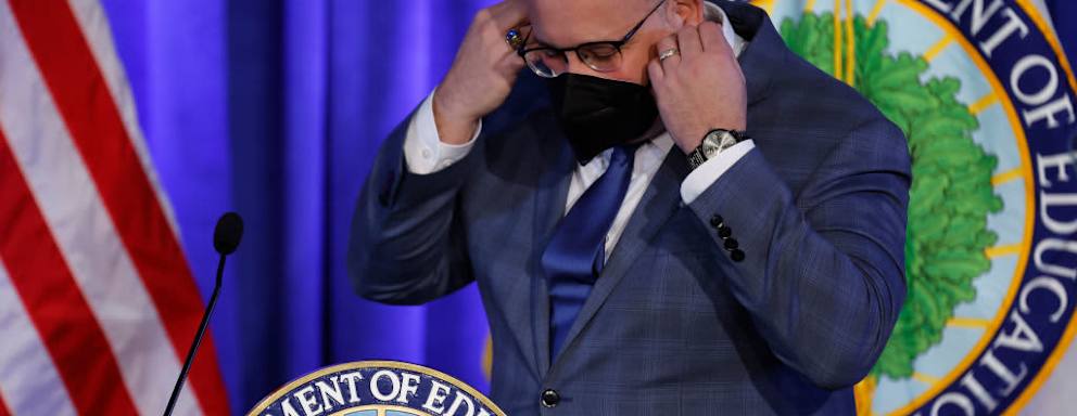 U.S. Education Secretary Miguel Cardona removes his face mask before delivering remarks at the department's Lyndon Baines Johnson Building in Washington, DC.