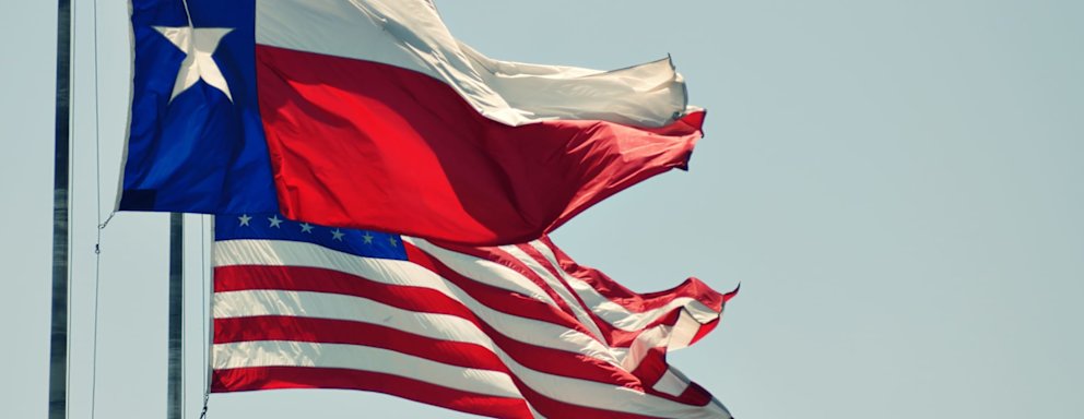 The Texas state flag and the USA flag blowing in the wind side by side.