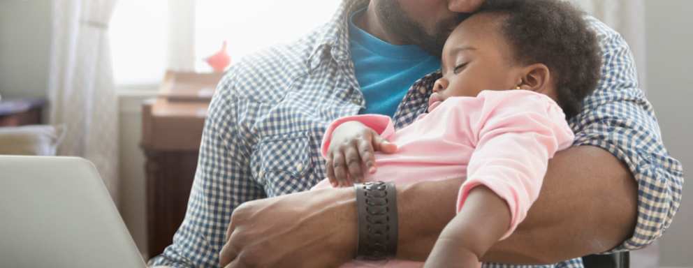 Father holding baby daughter and working from home