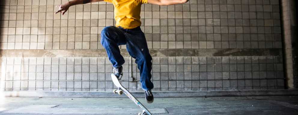 Female skateboarder performing jump in warehouse environment