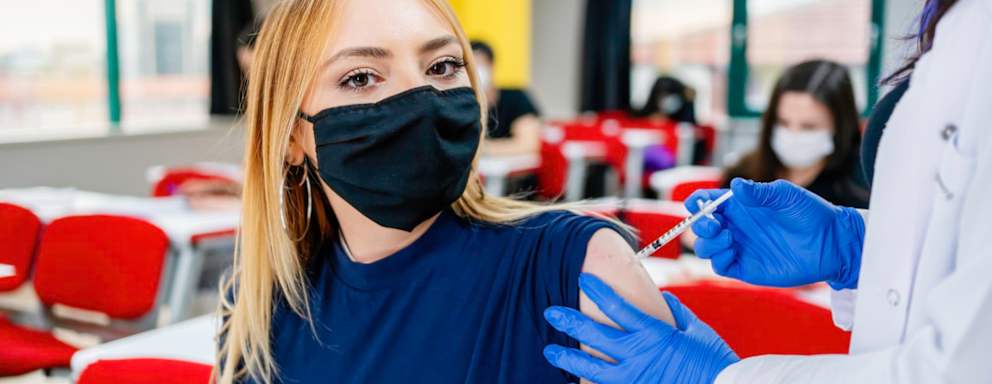 Nurse gives students a vaccination in school during coronavirus pandemic