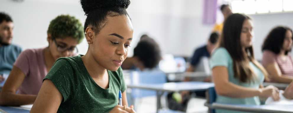 High school student taking an exam in a classroom full of other students.