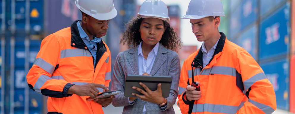 Logistic engineers and businesswomen are managed and confirm shipment on a digital tablet They are discussing the loading and unloading of cargo containers and trucks, including coordinating with crane operators at the cargo container yard.