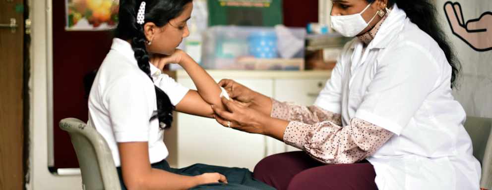 School nurse putting bandage on student's arm