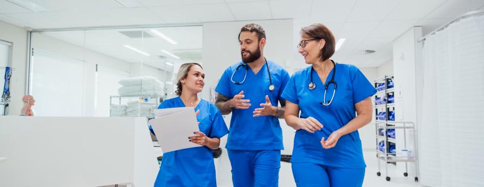 Three nurses walking and talking together in a hospital