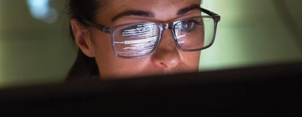 Close-up of a female computer programmer writing code on her desktop computer at work.