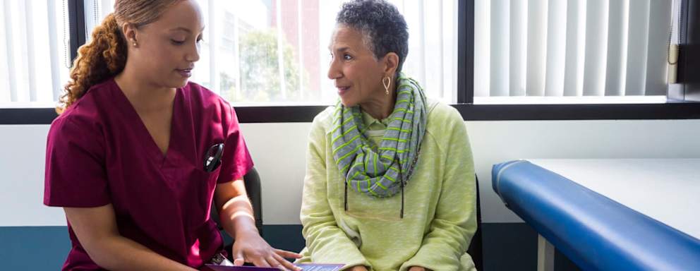 Black nurse talking to black patient