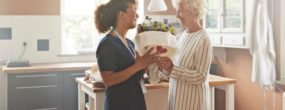 Patient giving nurse caregiver bouquet of flowers