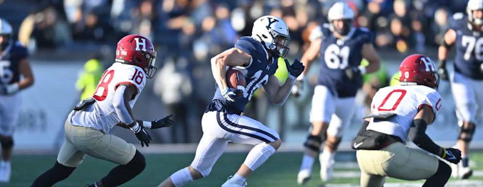 Football players on a field during a Harvard vs Yale game