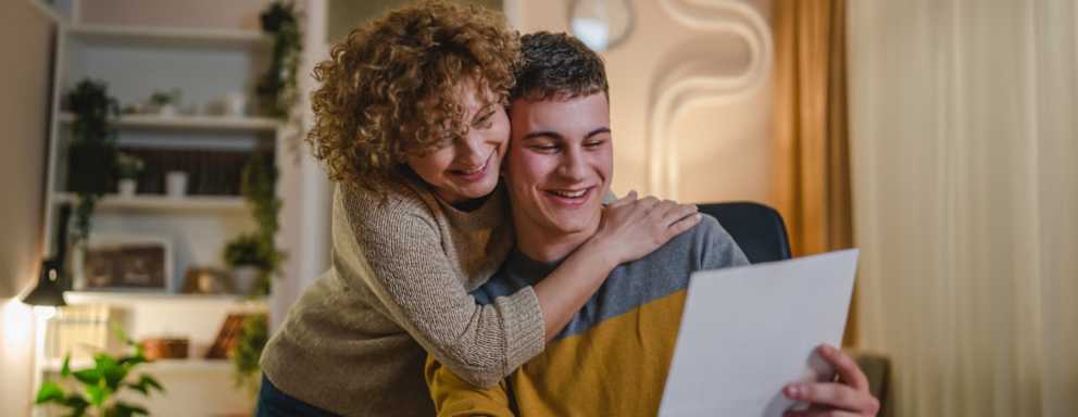 A high school student is excited as he shows his mother the financial aid award letter he received in the mail from his chosen college.