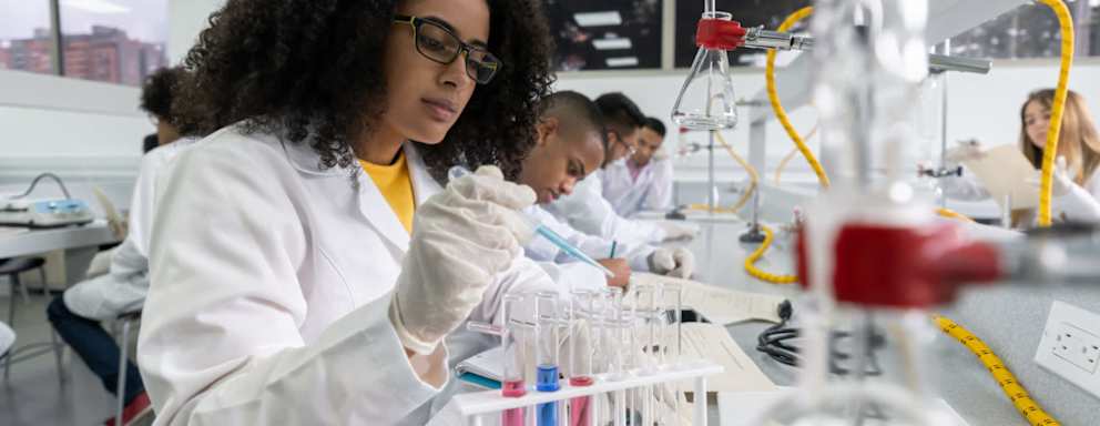Black female college student in a science class making experiments at the lab using test tubes and pipettes.